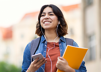 A young person with a notebook in one hand and a phone in the other