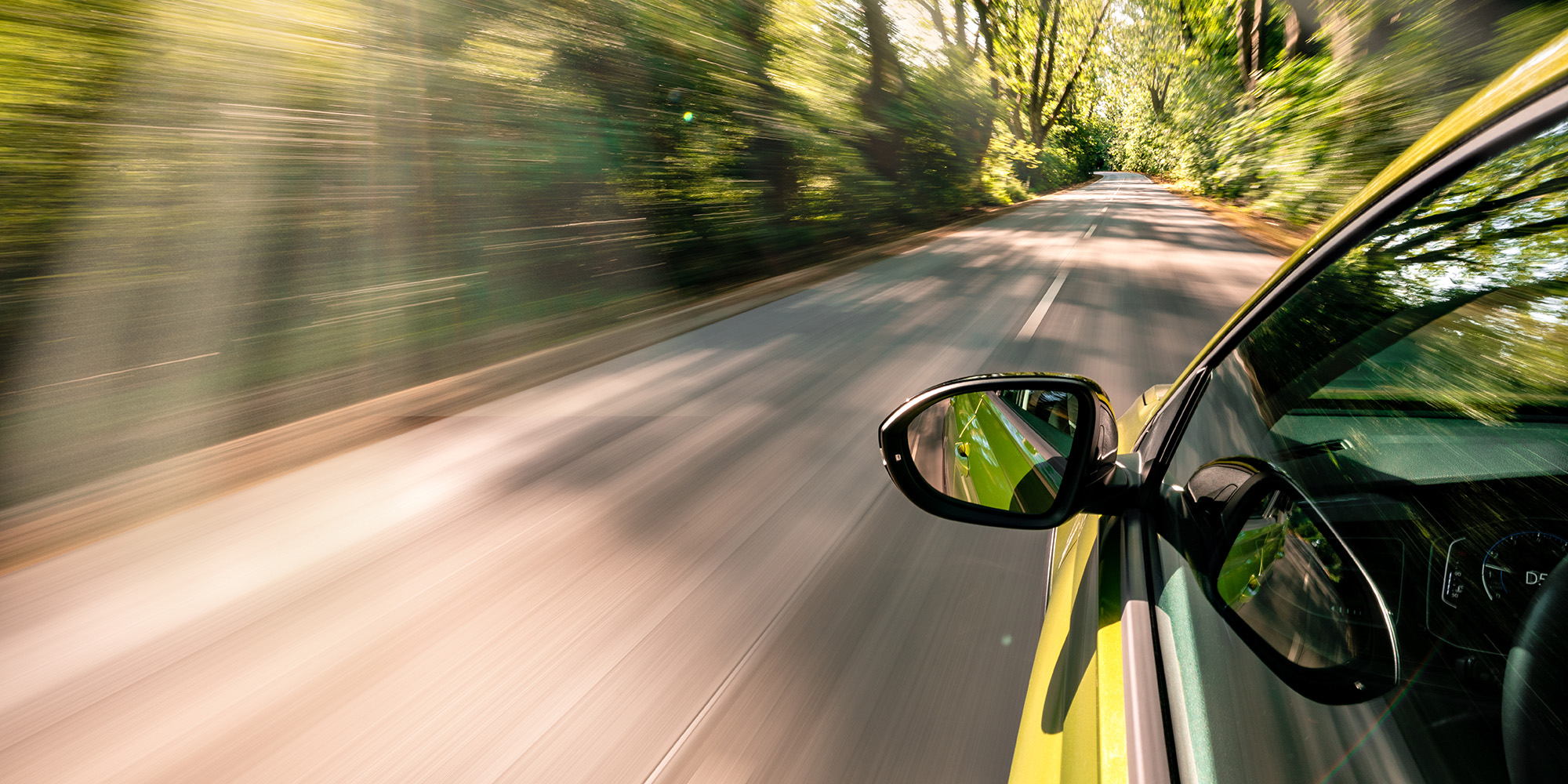 Car driving down forest road.