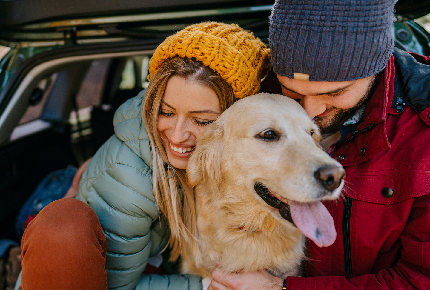 Two people and a dog in the back of a car